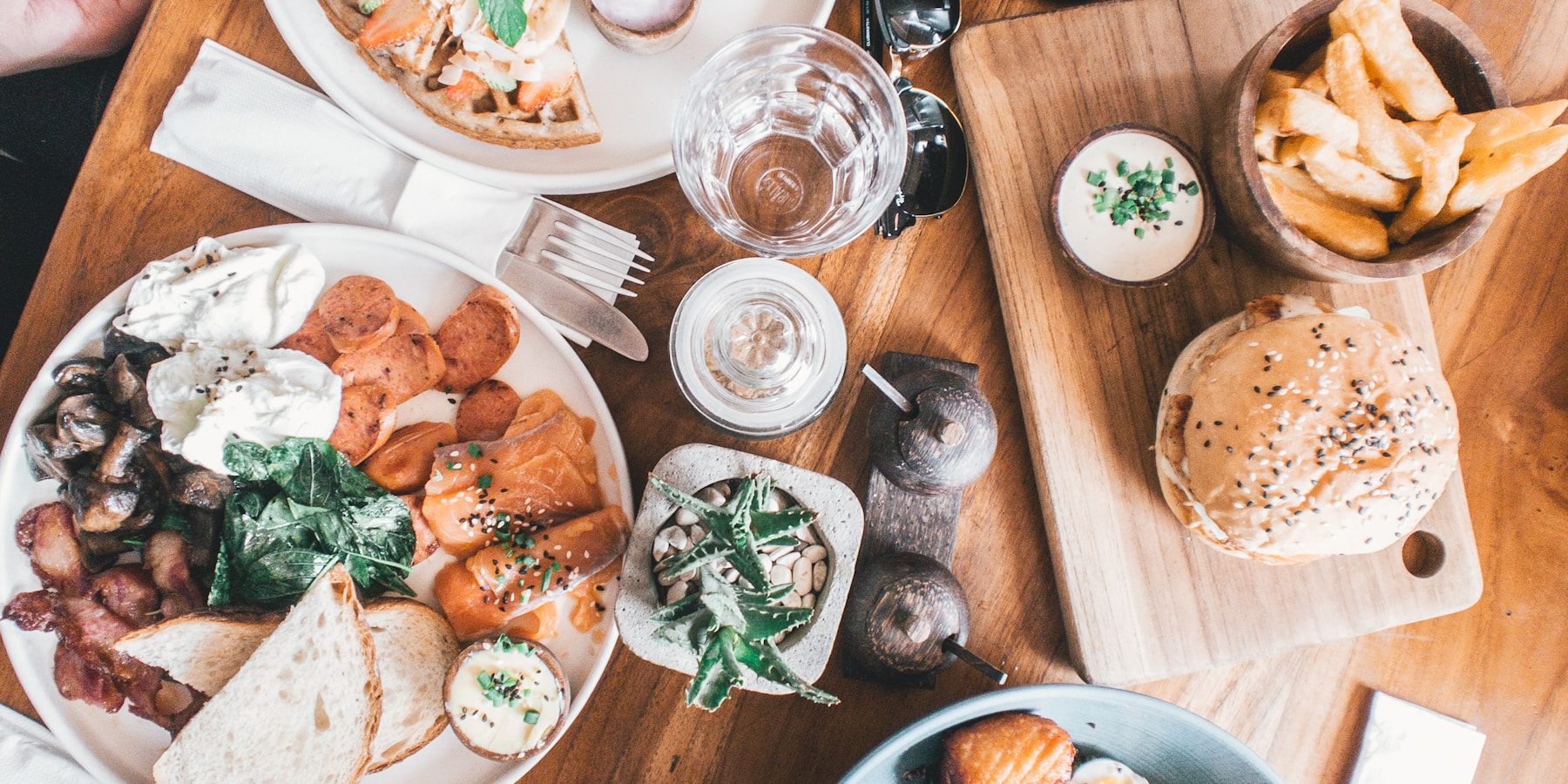 An overhead spread of brunch plates on a wooden table